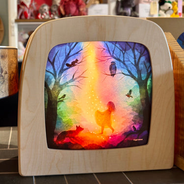 A Toverlux wooden light box with a curved top, featuring a colorful stained-glass style window depicting a fairy silhouette in a forest with rainbow light beams, birds, and trees.