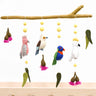 Colorful bird mobile hanging from a branch with a white background