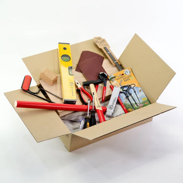 Open cardboard box filled with various tools on a white background
