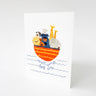 A white greeting card featuring a whimsical illustration of Noah's Ark with safari animals and the text 'Welcome little one' in blue script, shown standing against a light gray background.