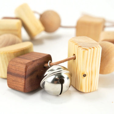 A wooden pram chain with beads and bells on a white background