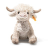 Plush toy highland cow with a visible brand tag on a white background