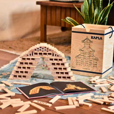 Kapla wooden planks set with a book and architectural design on a table.