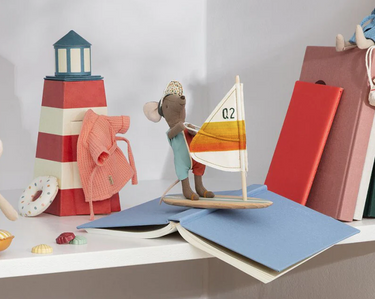 Toy Maileg mouse with a sailboat and lighthouse on a shelf