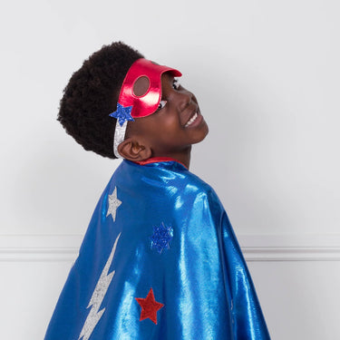 Child wearing a superhero costume with a blue cape and red mask against a white background