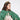 Young girl wearing a green tulle cape with red heart designs and gold accents on a white background.