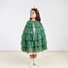 Child wearing a green tiered Christmas Tree cape with decorative elements on a white background