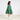 Child wearing a green tiered Christmas Tree themed cape with Christmas details on a white background