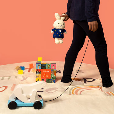 Child playing with toys on a bed against a pink wall