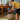 A child storing toys in his Stapelstein Dynamic Sitting set. he has a yellow striped t-shirt, black shorts and is in a blue room with toys and games. 